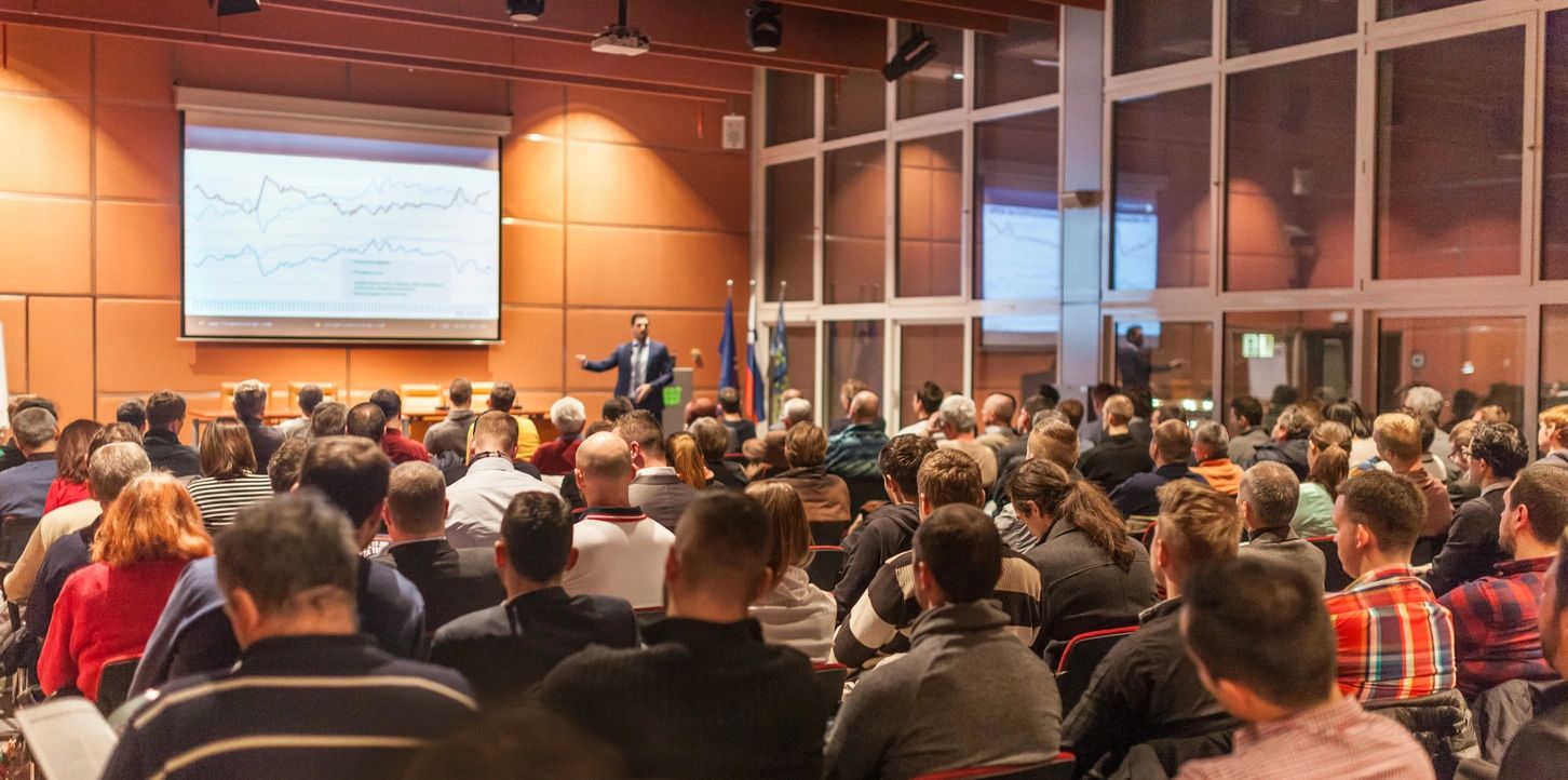 a packed audience faces a conference presenter