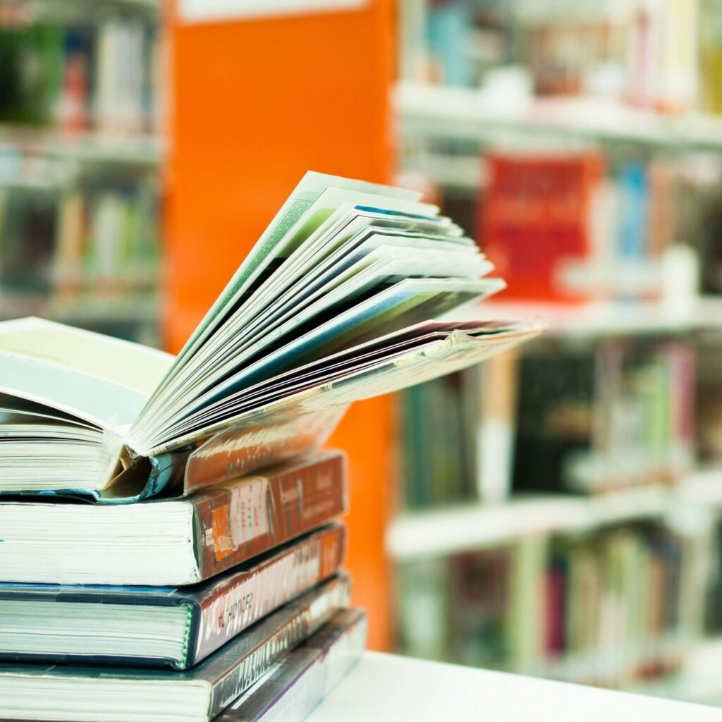 A stack of books in a library, one open.